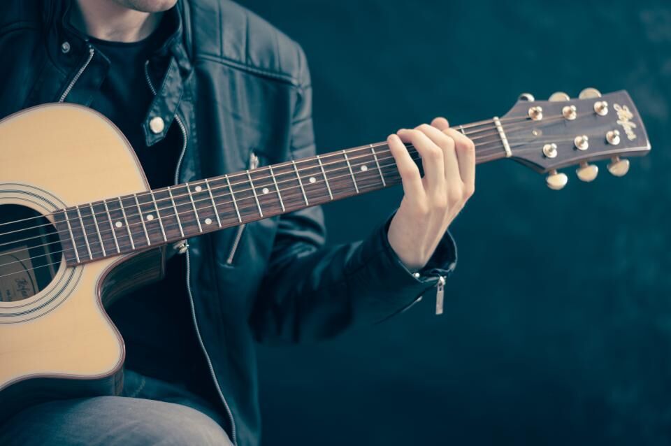 Hands playing an acoustic guitar