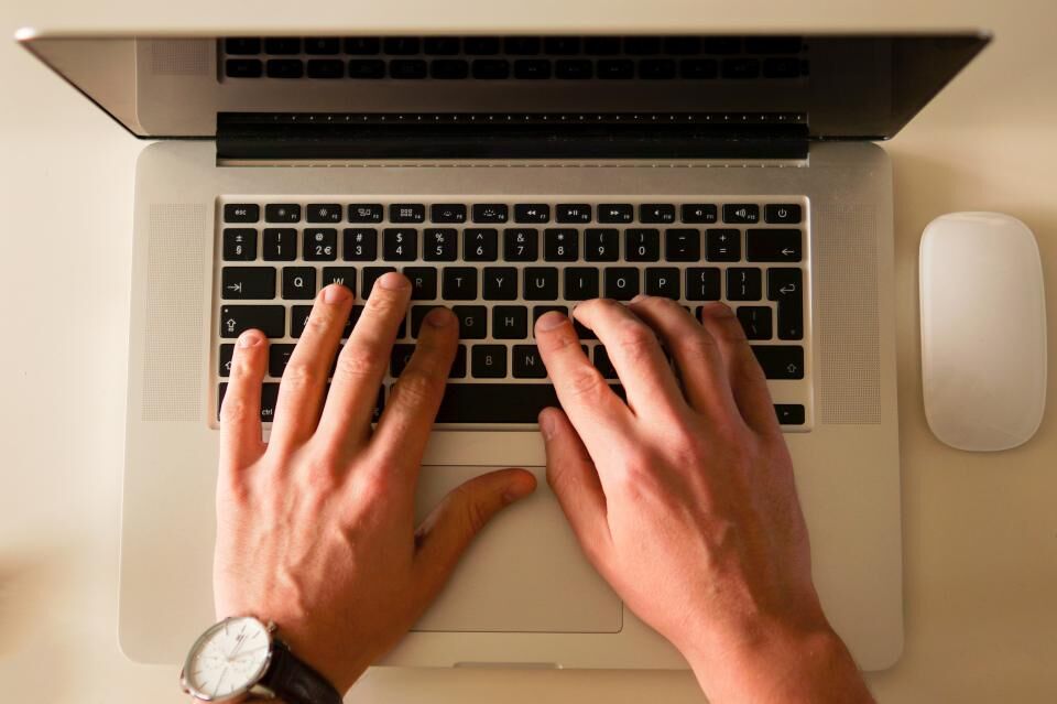 Hands typing on a laptop